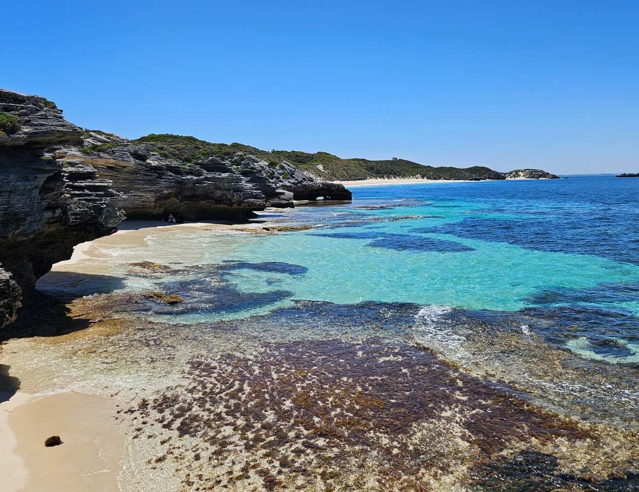 Weißer Sandstrand auf Rottnest Island mit türkisblauem Wasser und unberührter Natur im Hintergrund
