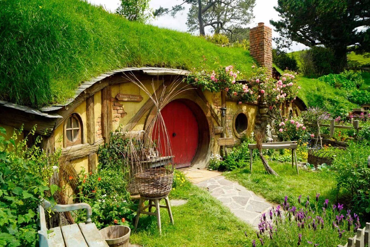 Eingang zu Bilbos Haus Bag End im Hobbiton Movie Set, umgeben von bunten Blumen und der bekannten runden Tür.