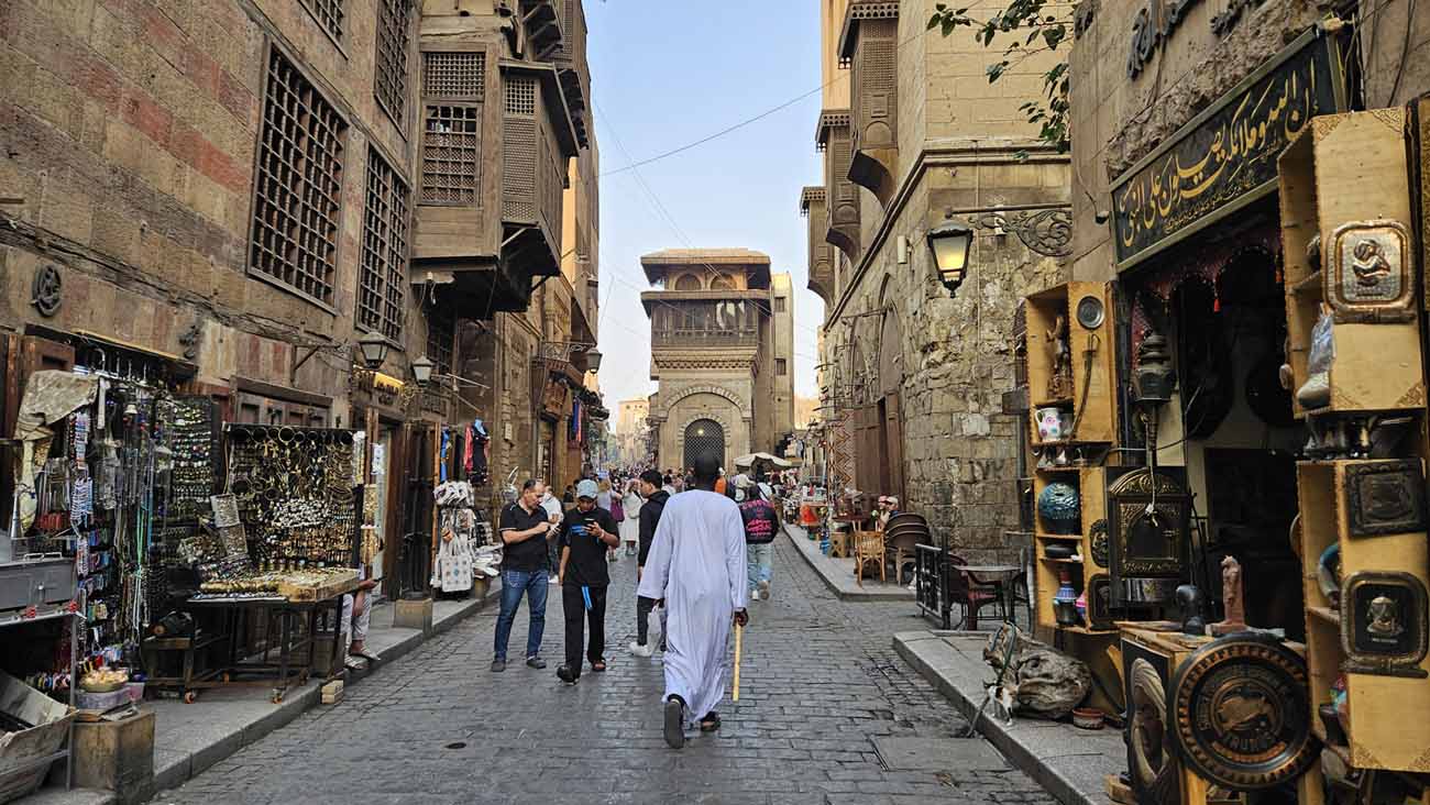 Historische Moez Street in Kairo mit alten Gebäuden, Geschäften und Straßenleben.