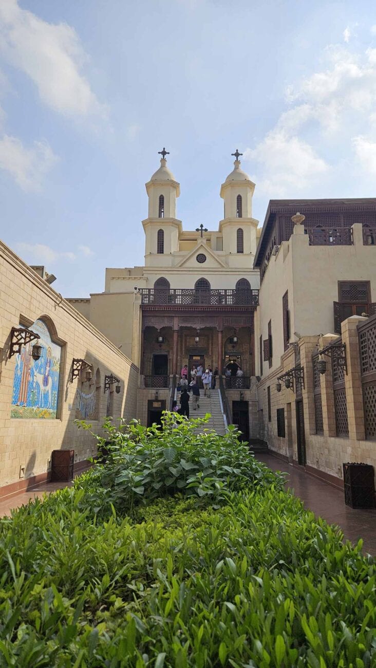 Hängende Kirche im koptischen Viertel von Kairo, umgeben von Sicherheitskontrollen und Tourbussen.